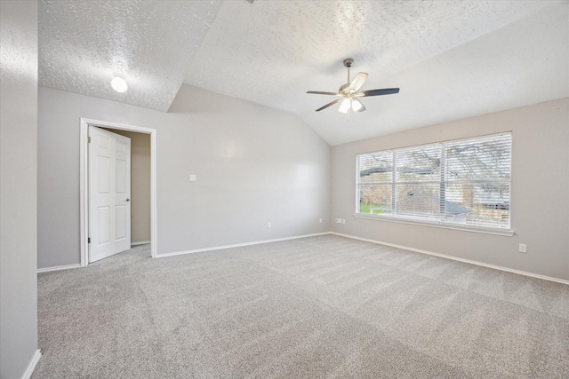 carpeted spare room featuring baseboards, a textured ceiling, ceiling fan, and vaulted ceiling