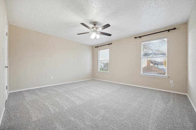 carpeted spare room with a textured ceiling, baseboards, and ceiling fan