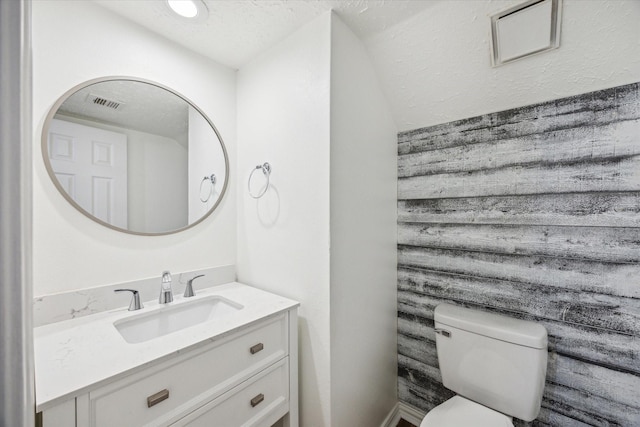 bathroom with visible vents, toilet, a textured ceiling, and vanity