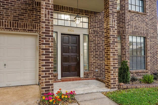 doorway to property featuring a garage and brick siding