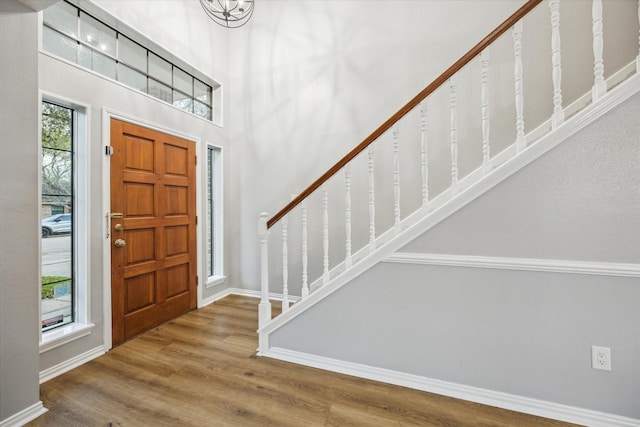 entrance foyer with a high ceiling, stairs, baseboards, and wood finished floors