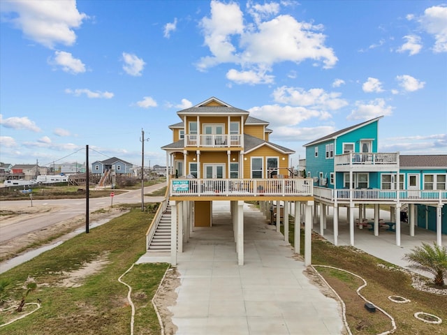 1018 Seashell Dr, Surfside Beach, TX 77541 - view of front facade with a carport, a balcony, driveway, stairs, and french doors