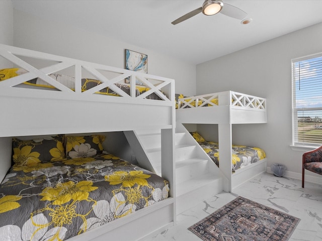 bedroom featuring baseboards, marble finish floor, and ceiling fan