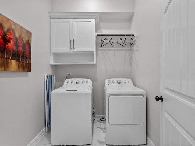 clothes washing area with cabinet space, marble finish floor, baseboards, and separate washer and dryer