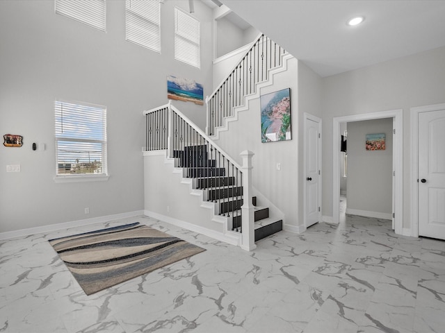 1018 Seashell Dr, Surfside Beach, TX 77541 - staircase with marble look tile flooring, a high ceiling, and recessed lighting