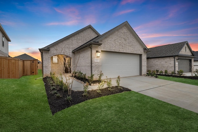 view of front facade featuring driveway, a front lawn, fence, an attached garage, and brick siding