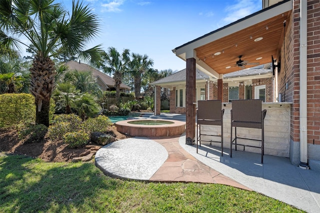 view of patio / terrace featuring outdoor dry bar, an in ground hot tub, ceiling fan, and fence