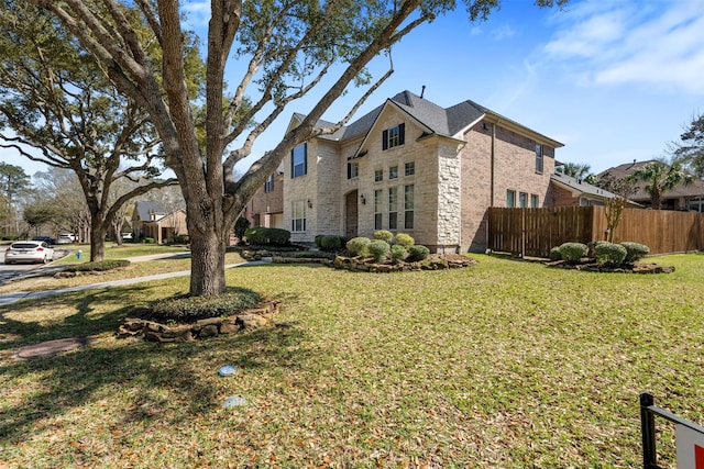 view of side of home with a yard, stone siding, and fence