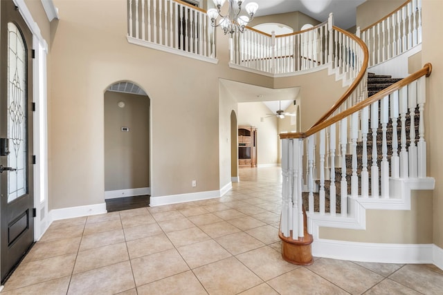 entrance foyer with arched walkways, tile patterned flooring, stairway, and baseboards