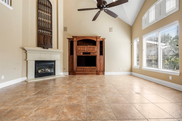 unfurnished living room with tile patterned floors, high vaulted ceiling, a ceiling fan, baseboards, and a tile fireplace