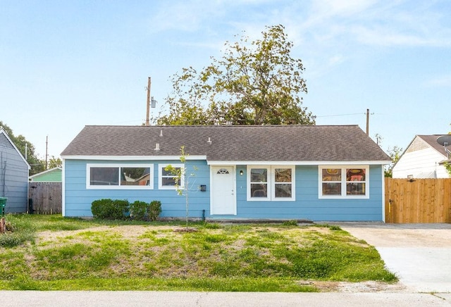 ranch-style home featuring a front yard, fence, and roof with shingles