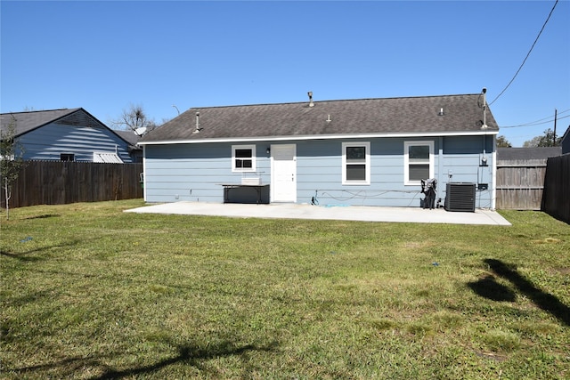 rear view of house with roof with shingles, a fenced backyard, central air condition unit, a patio area, and a lawn