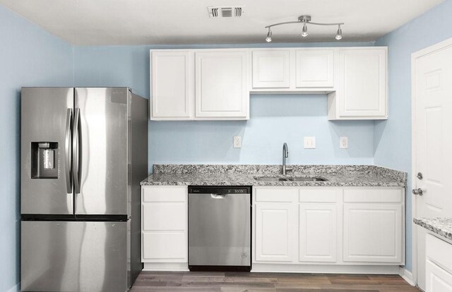 kitchen with wood finished floors, white cabinets, stainless steel appliances, and a sink