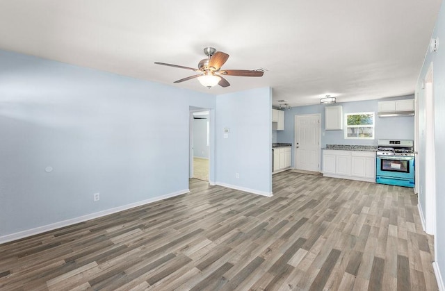 kitchen with stainless steel gas stove, a ceiling fan, light wood-style floors, white cabinets, and baseboards