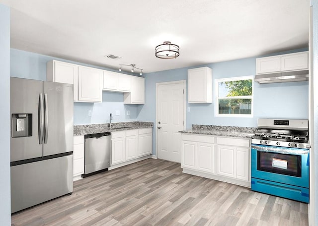 kitchen with visible vents, a sink, under cabinet range hood, appliances with stainless steel finishes, and white cabinetry