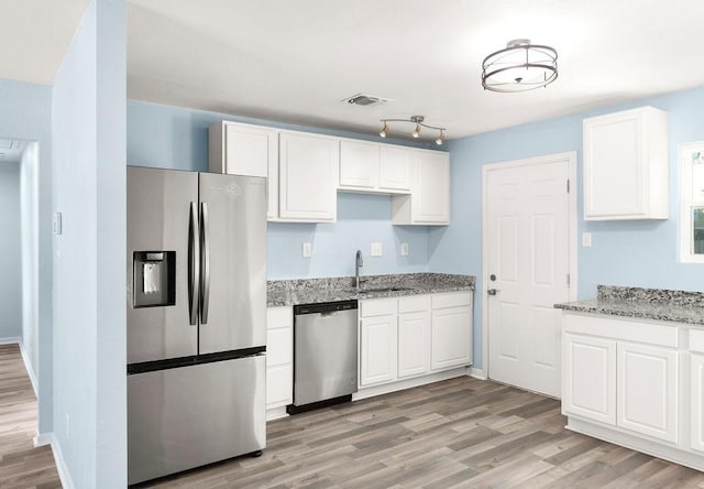 kitchen with a sink, light stone countertops, visible vents, and stainless steel appliances