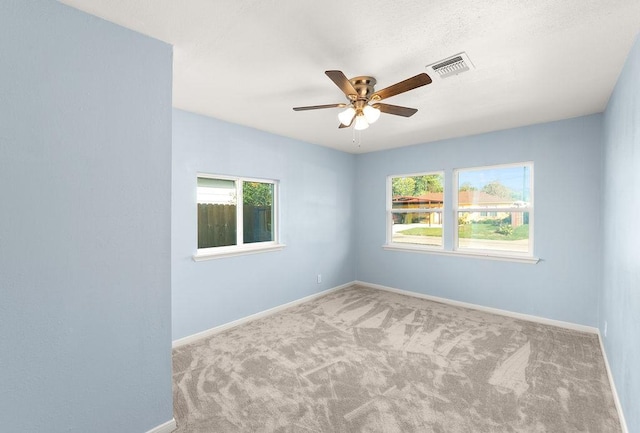 spare room with visible vents, plenty of natural light, baseboards, and carpet flooring