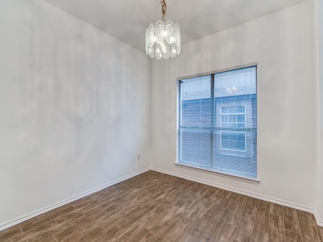 unfurnished room featuring dark wood-type flooring, a notable chandelier, and baseboards