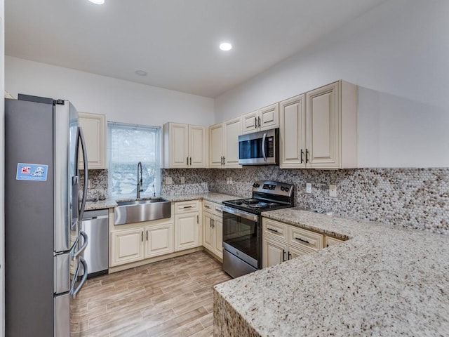 kitchen with a sink, stainless steel appliances, light stone countertops, and backsplash