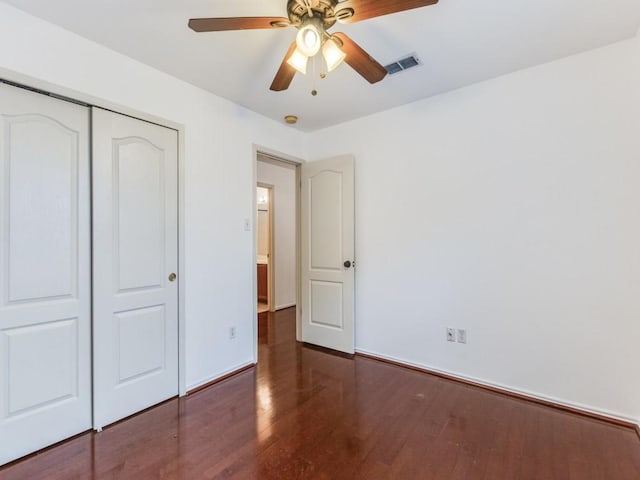 unfurnished bedroom with wood finished floors, visible vents, baseboards, ceiling fan, and a closet