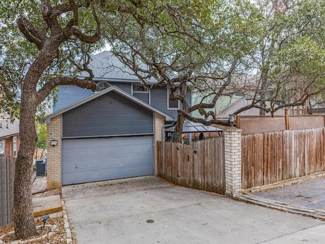 garage featuring concrete driveway and fence