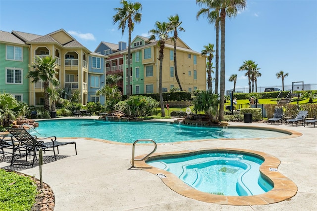 pool featuring a patio area, a residential view, a hot tub, and fence