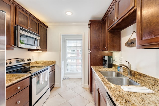 kitchen with light tile patterned floors, light stone countertops, ornamental molding, a sink, and appliances with stainless steel finishes