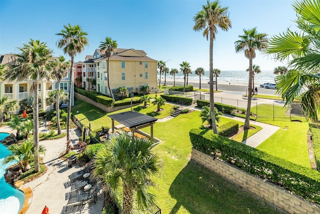 view of community with fence, a lawn, and a water view