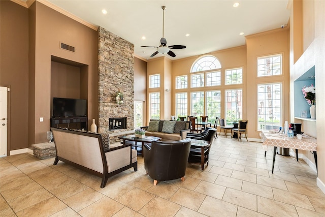 living room with visible vents, a high ceiling, a stone fireplace, and ornamental molding