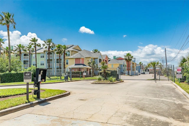 view of street featuring a gate, curbs, street lights, a gated entry, and a residential view