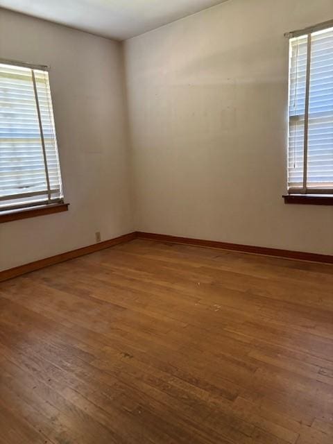 unfurnished room with baseboards and wood-type flooring