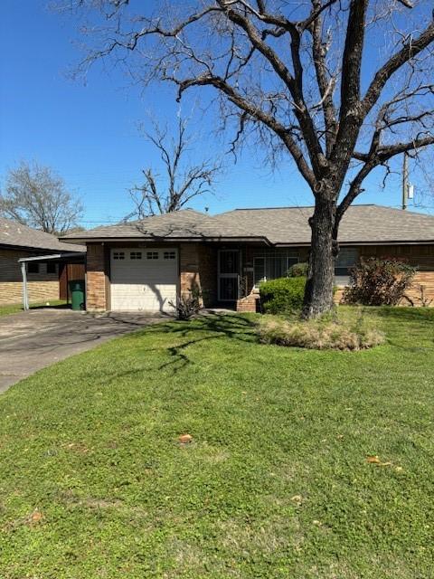 single story home with a front lawn, an attached garage, and driveway