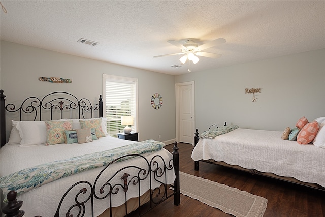 bedroom with visible vents, a textured ceiling, dark wood-type flooring, and ceiling fan