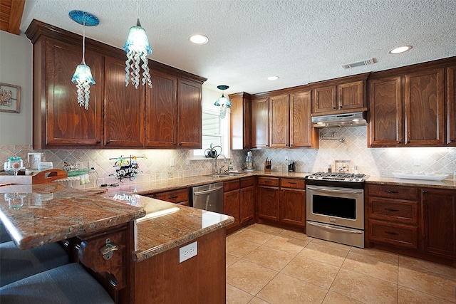 kitchen featuring under cabinet range hood, dark stone countertops, a sink, stainless steel appliances, and a peninsula