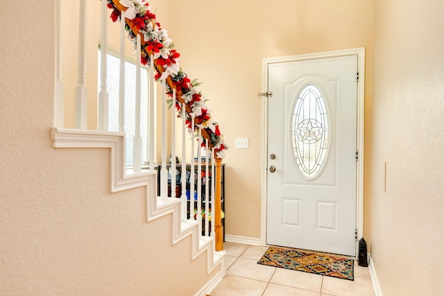 entryway with tile patterned flooring, stairs, and baseboards