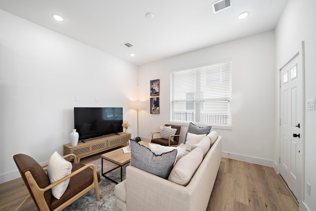 living room with recessed lighting, wood finished floors, and visible vents