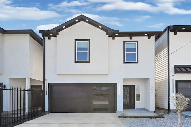 view of front of home with stucco siding, driveway, a garage, and fence