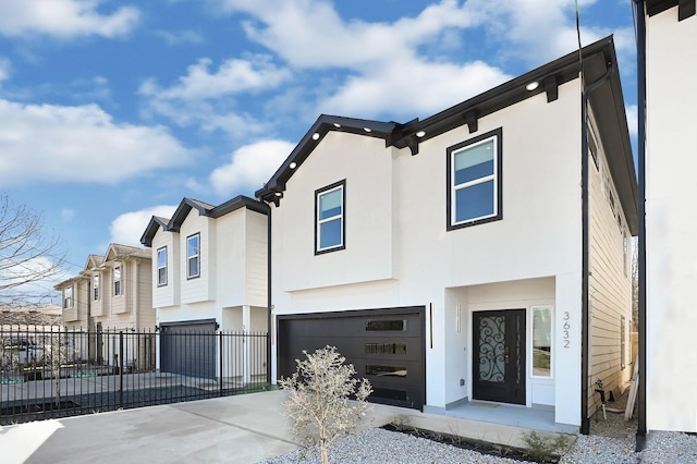 view of front of house featuring fence, an attached garage, stucco siding, concrete driveway, and a residential view