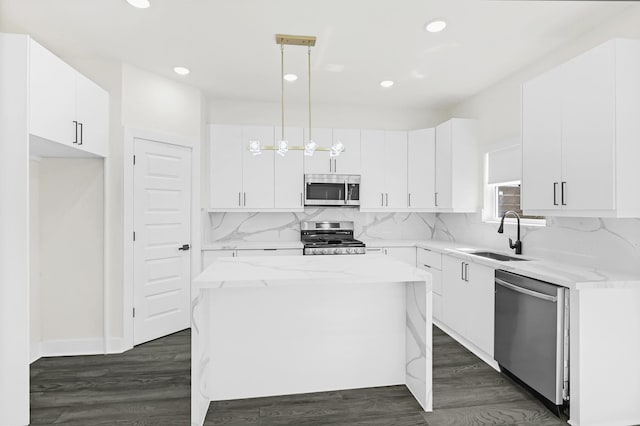 kitchen featuring backsplash, a center island, appliances with stainless steel finishes, white cabinetry, and a sink