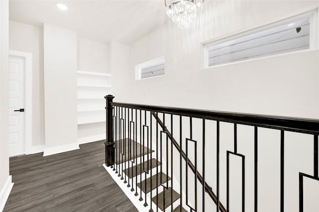 hallway featuring dark wood-style floors, baseboards, recessed lighting, a notable chandelier, and an upstairs landing