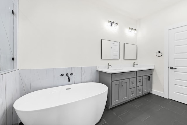 bathroom with a freestanding bath, double vanity, wainscoting, and a sink