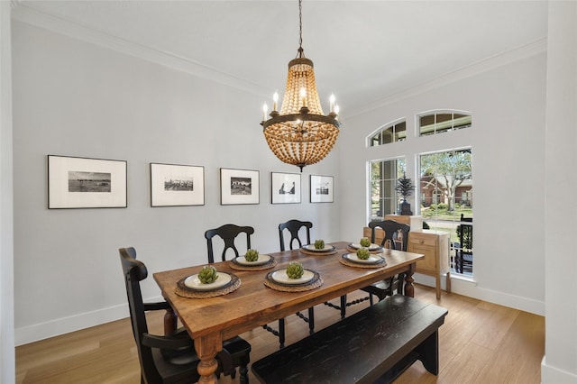 dining space with an inviting chandelier, crown molding, light wood-type flooring, and baseboards