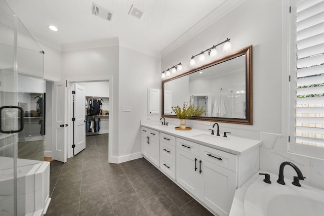 bathroom with a spacious closet, visible vents, crown molding, and a sink