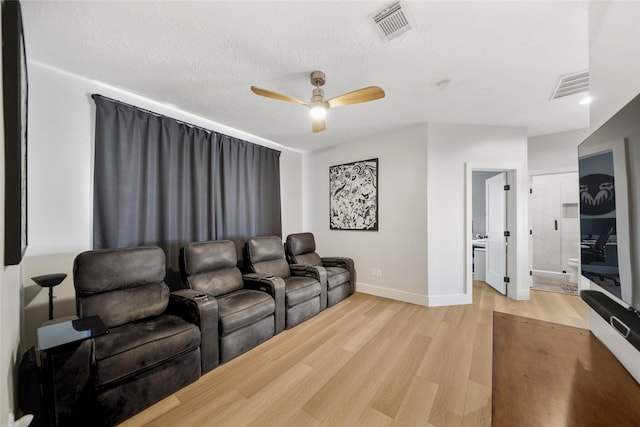 cinema room with light wood-type flooring, visible vents, baseboards, and a ceiling fan