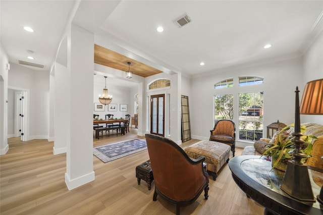 living area featuring visible vents, baseboards, crown molding, and light wood finished floors