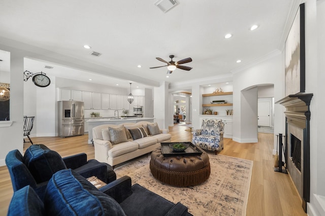 living room with visible vents, baseboards, light wood-style flooring, and a fireplace