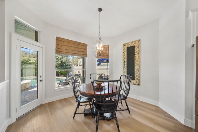 dining space with an inviting chandelier, light wood-style flooring, and baseboards