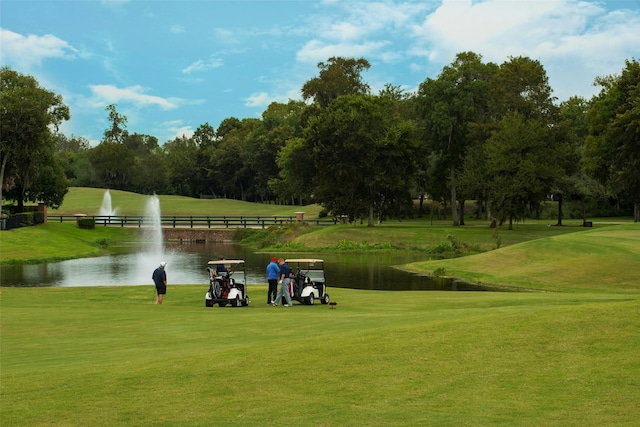 view of home's community featuring view of golf course, a yard, and a water view