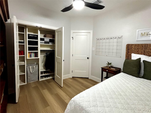 bedroom with a ceiling fan, wood finished floors, visible vents, and baseboards