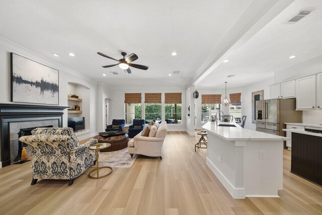 living area featuring visible vents, recessed lighting, a tile fireplace, light wood-style floors, and crown molding